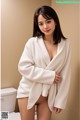 A woman in a white robe standing in a bathroom.