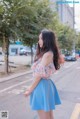 A woman in a blue skirt is standing on the street.