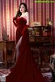 A woman in a red dress standing in front of a piano.