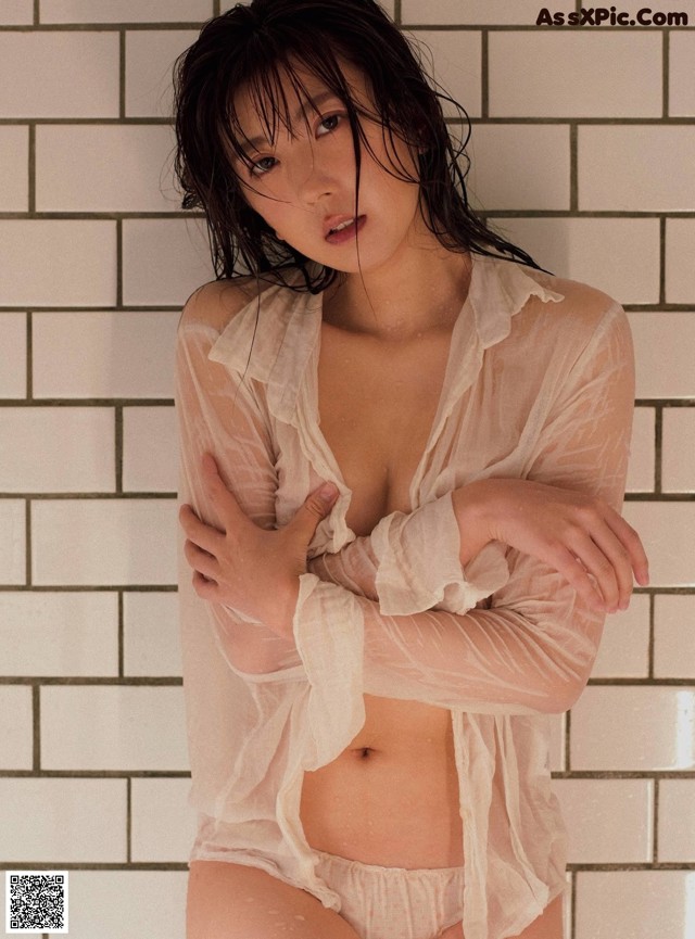 A woman in a white shirt is posing in a bathroom.