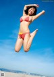 A woman in a red bikini jumping in the air.