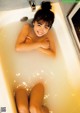 A woman sitting in a bathtub with her legs in the water.