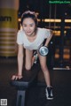 A woman is doing push ups with dumbbells in a gym.