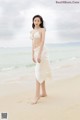 A woman in a white bikini standing on a beach.