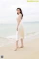 A woman in a white dress standing on a beach.