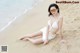 A woman in a white bikini sitting on the beach.