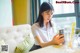 A woman sitting at a table looking at her phone.