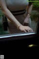 A woman in a black and white dress is opening a car door.