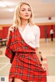 A woman in a white shirt and red plaid skirt posing for a picture.