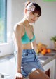 A woman in a blue bikini top and denim shorts sitting on a kitchen counter.