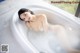 A woman laying in a bathtub with bubbles.