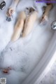 A woman is taking a bath in a bathtub filled with foam.