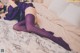 A woman laying on a bed wearing purple stockings.