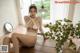 a woman sitting on top of a wooden table next to a plant