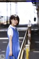 A woman in a blue dress standing on a train platform.