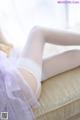 A woman in white stockings and a tutu laying on a couch.