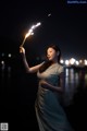 A woman holding a sparkler in her hand at night.