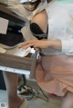 A woman in a white shirt and pink skirt sitting at a desk.