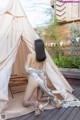 A woman sitting in front of a teepee on a wooden deck.