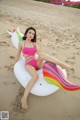 A woman in a pink bikini sitting on an inflatable unicorn.