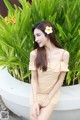 A woman sitting on a white bench with a flower in her hair.