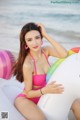 A woman in a pink bikini sitting on an inflatable unicorn.