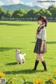 A girl in a school uniform standing in a field with a dog.