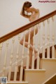 A naked woman is standing on the stairs. 