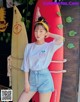 a woman standing next to a surfboard in front of a wall