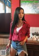 A woman in a red plaid shirt and denim shorts posing for a picture.