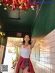 A woman in a white tank top and red plaid skirt posing for a picture.