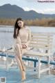 A woman sitting on a bench in front of a body of water.