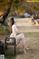 A woman sitting on a bench in a park.