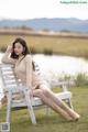 A woman sitting on a white bench in a field.