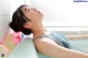 A woman laying in a bathtub filled with water and balloons.