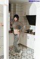 A woman standing in a kitchen next to a refrigerator.